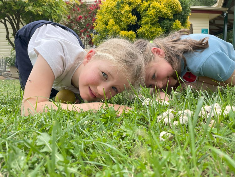 2 girls looking closely at the grass
